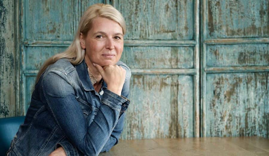 Porträtfoto von Ilse, die an einem Tisch sitzt. Sie verwendet SpeediCath Compact Female, um ihre Blasensymptome zu behandeln. 