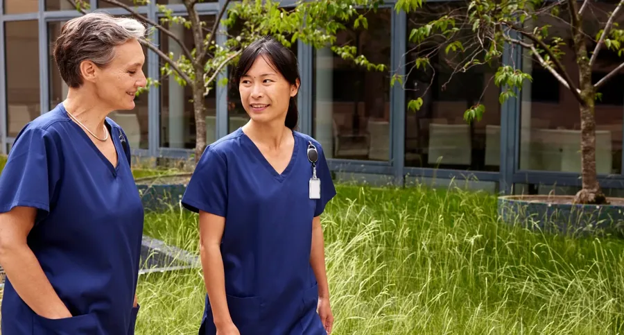 Bild von zwei medizinischen Fachkräften im Freien. Coloplast bietet sowohl TAI-Systeme mit hohem als auch mit niedrigem Volumen an.  