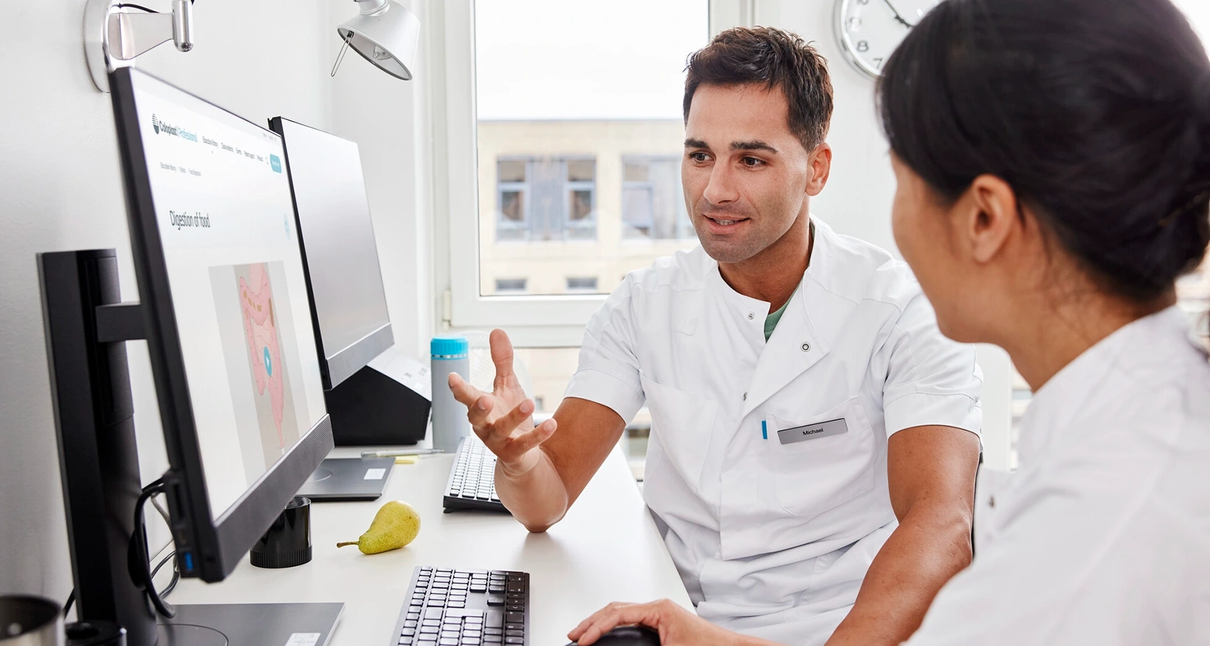 Foto von zwei medizinischen Fachkräften, die an einem Computer sitzen. Multiple Sklerose kann zu Darmfunktionsstörungen führen. Es gibt verschiedene Behandlungsmethoden, mit denen die Symptome behandelt und kontrolliert werden können.  