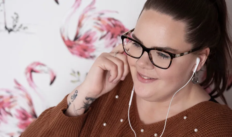 Porträtfoto von Sarah, die Musik hört. Bei Sarah wurde MS diagnostiziert und sie verwendet Einmalkatheter, um ihre Blase zu entleeren.  